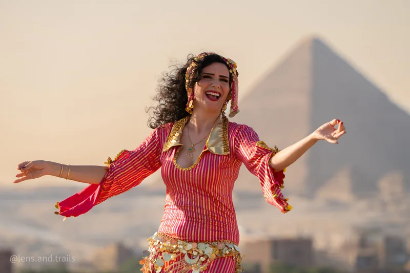 Lachende Taenzerin mit ausgebreiteten Armen vor der Pyramide