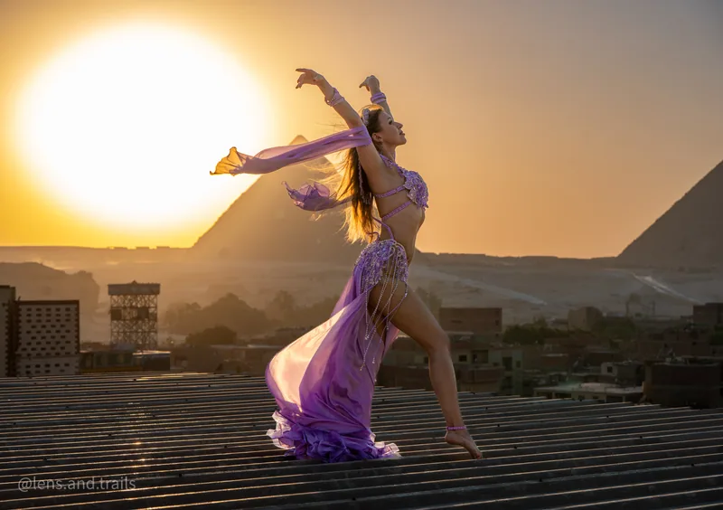 Dramatische Rueckbeuge in Lila vor goldener Pyramide