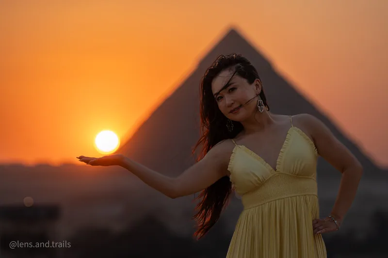 Frau im gelben Kleid haelt die Sonne in der Hand