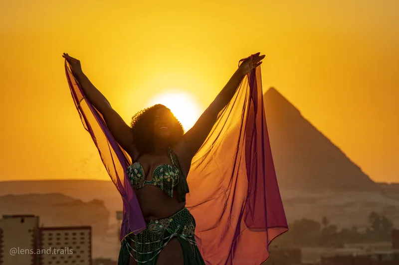 Silhouette mit erhobenen Armen und Schleier vor Pyramide