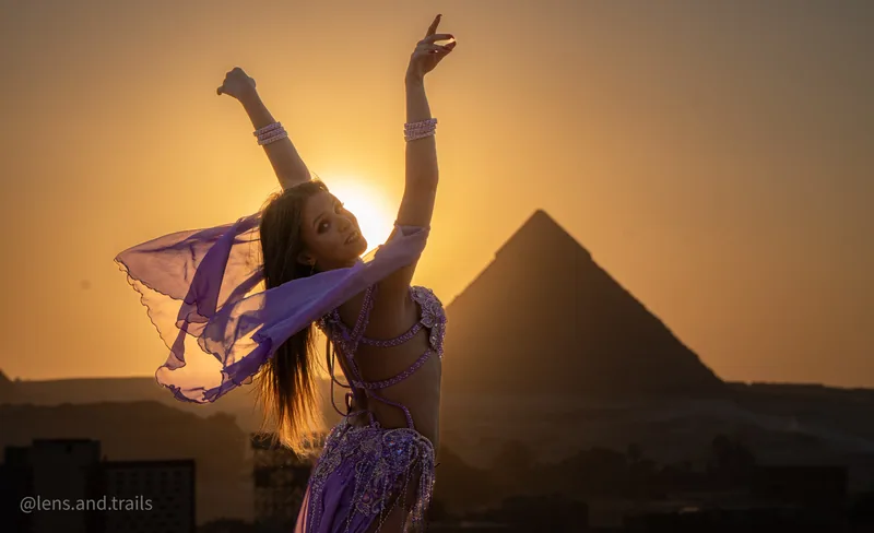 Taenzerin in Lila greift zum Himmel vor Pyramide