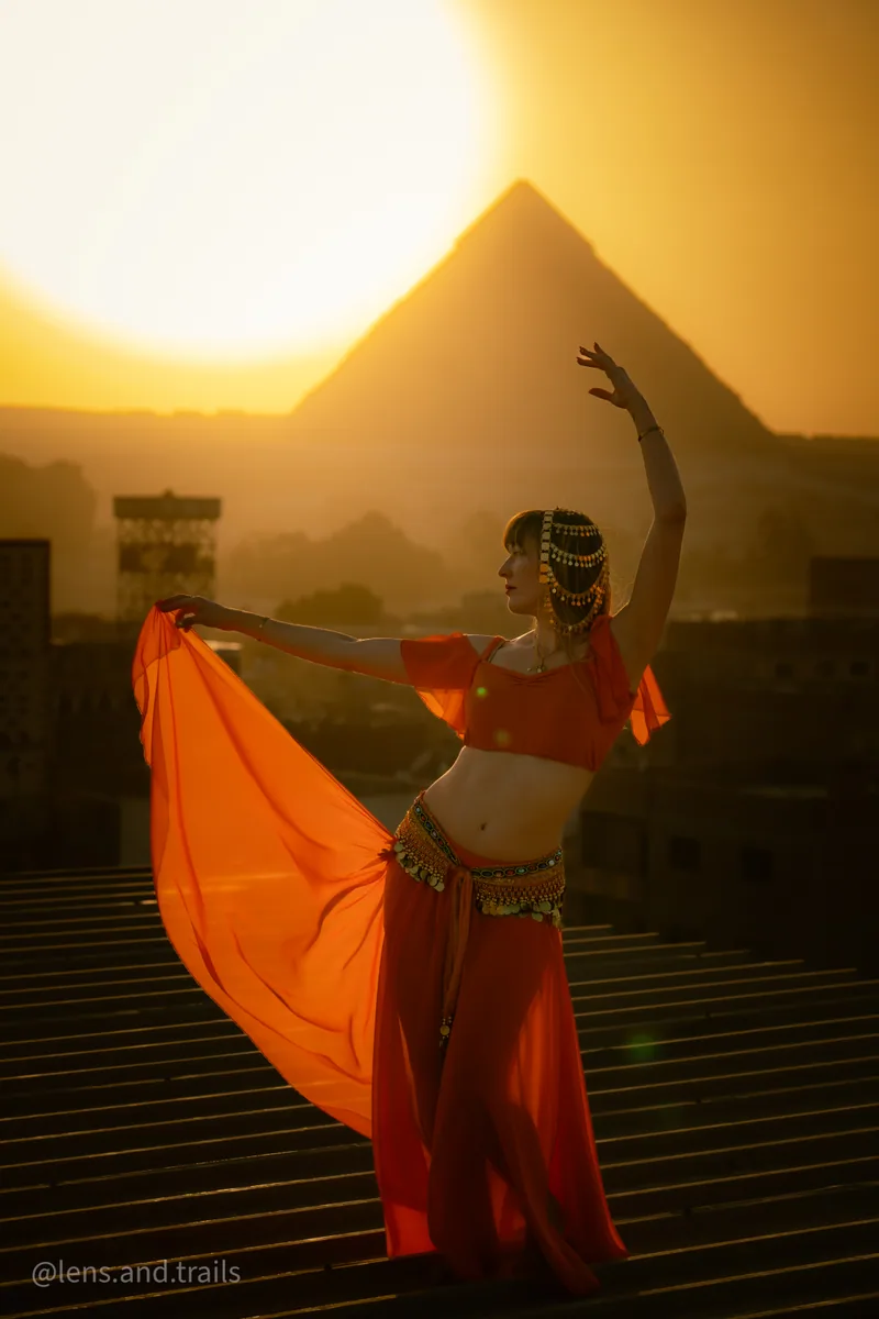 Taenzerin in Orange mit fliessendem Stoff vor Pyramide